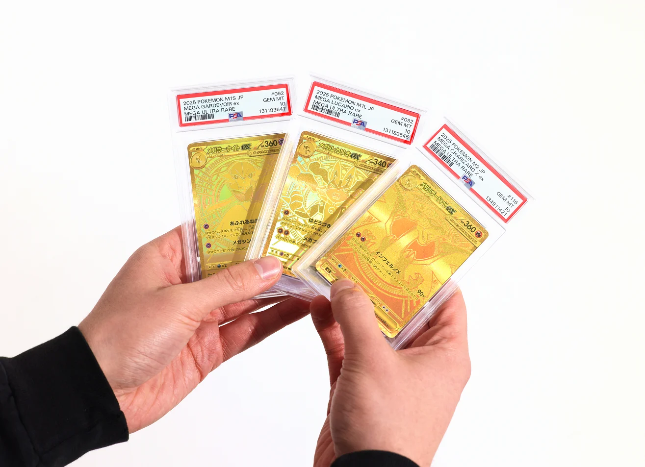 A collector holding three PSA Gem Mint 10 graded Pokémon cards